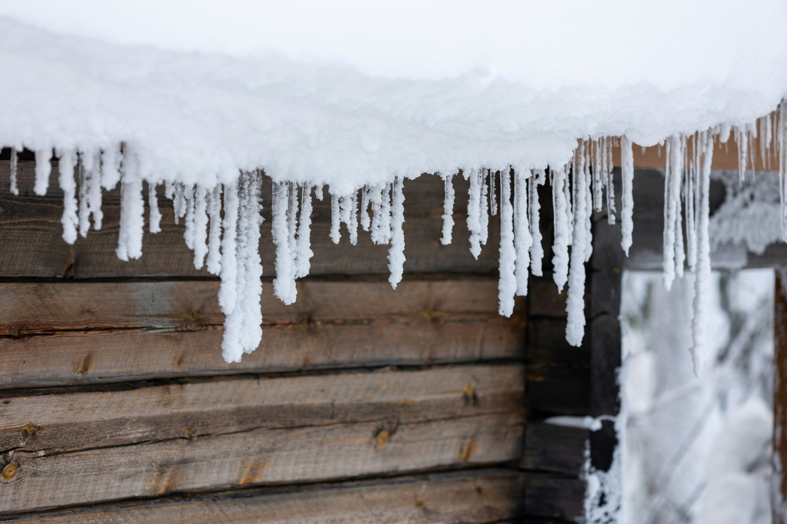 Thick ice buildup along the edge of a snow covered residential roof