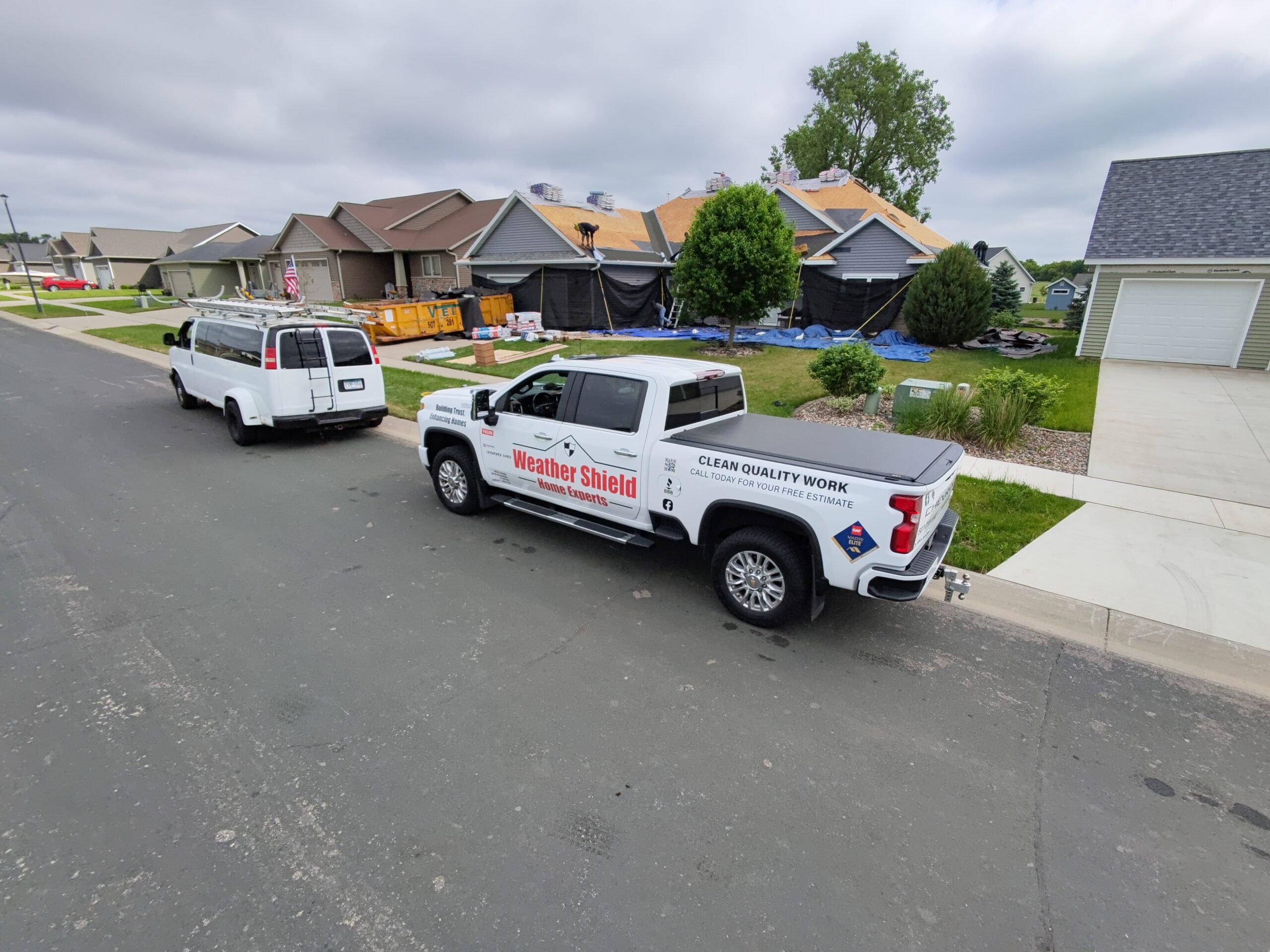 A contractor examines a residential asphalt shingle roof on a clear fall day.